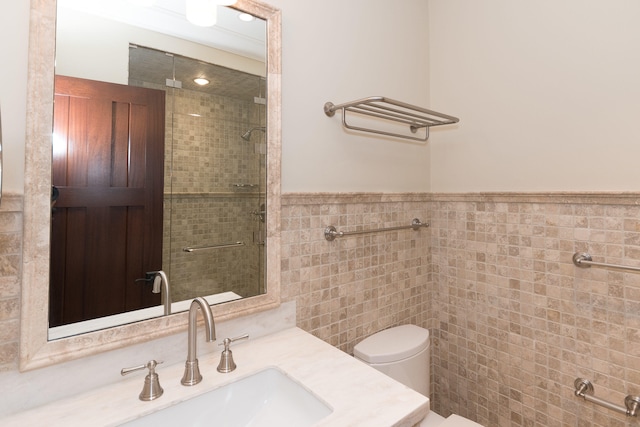 bathroom featuring a shower with door, vanity, tile walls, and toilet