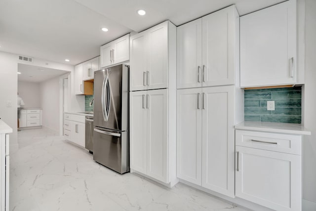 kitchen with tasteful backsplash, appliances with stainless steel finishes, and white cabinets