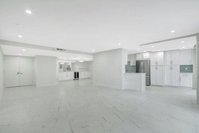 unfurnished living room featuring floor to ceiling windows, beverage cooler, and a chandelier