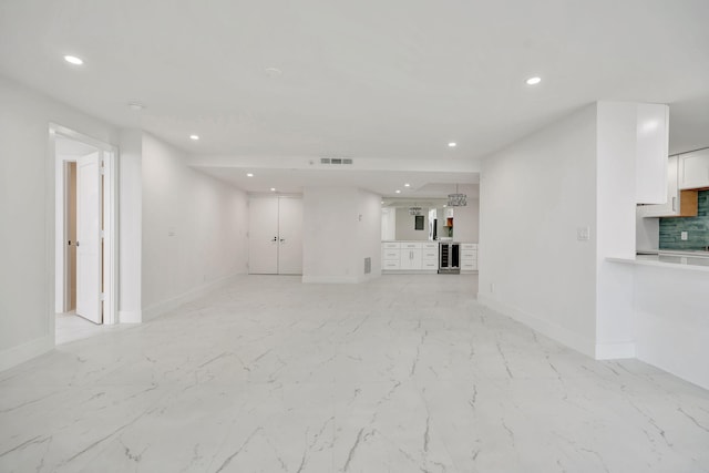 unfurnished living room featuring wine cooler and indoor bar