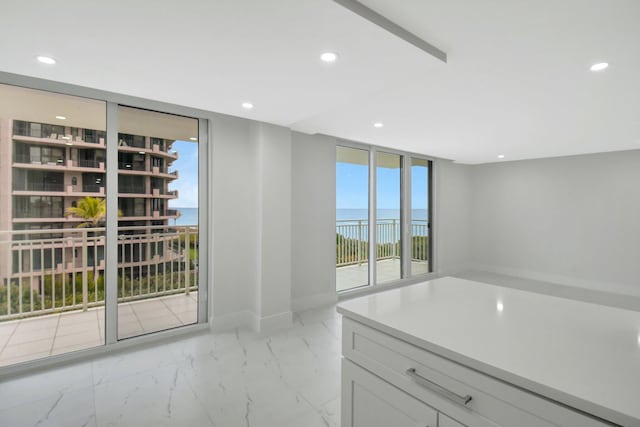 interior space featuring a wall of windows, recessed lighting, marble finish floor, and baseboards