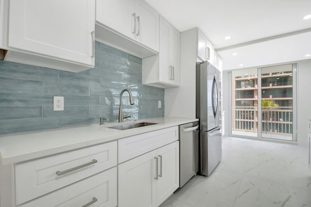 kitchen featuring stainless steel appliances, a sink, white cabinets, marble finish floor, and tasteful backsplash