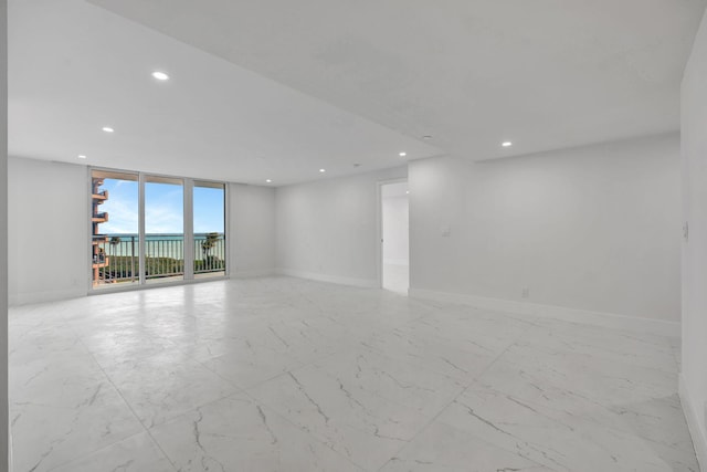 unfurnished room with recessed lighting, floor to ceiling windows, and baseboards