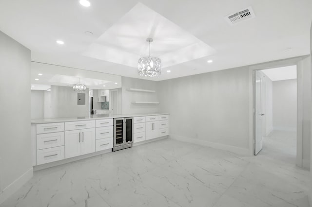 bar with a tray ceiling, marble finish floor, visible vents, beverage cooler, and baseboards