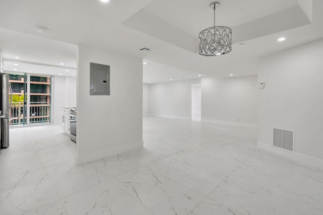 spare room featuring baseboards, a raised ceiling, visible vents, and electric panel