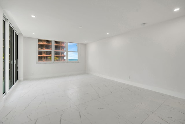 unfurnished room with marble finish floor, baseboards, and recessed lighting