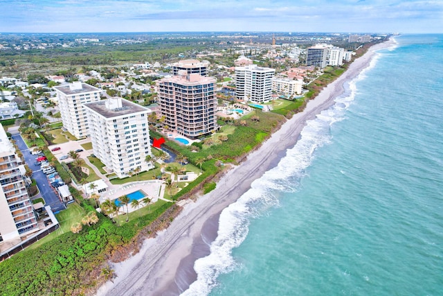 drone / aerial view featuring a water view, a view of the beach, and a city view