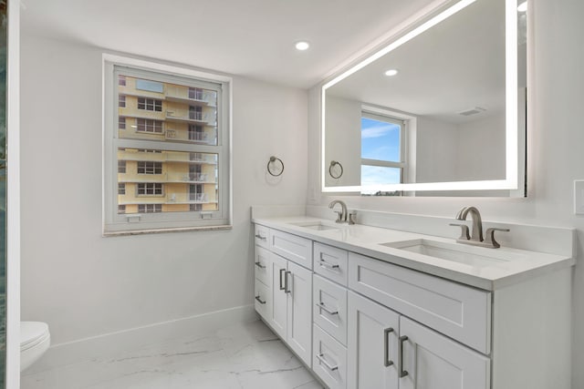 bathroom featuring marble finish floor, a sink, baseboards, and double vanity