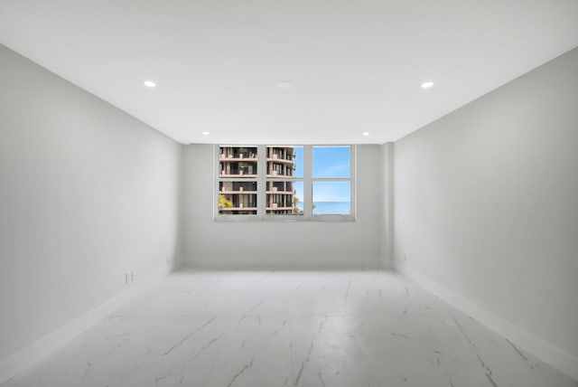 unfurnished room with marble finish floor, baseboards, and recessed lighting