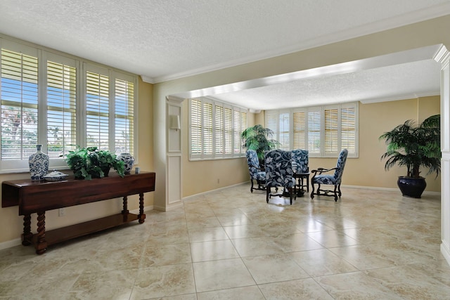 interior space featuring a textured ceiling, light tile patterned floors, baseboards, and crown molding