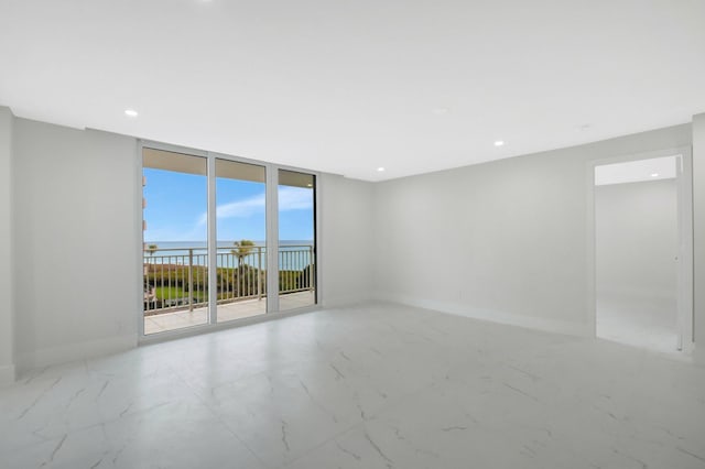 unfurnished room with marble finish floor, a wall of windows, recessed lighting, and baseboards