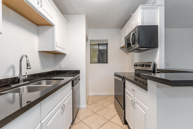 kitchen featuring appliances with stainless steel finishes, a textured ceiling, sink, light tile patterned floors, and white cabinets