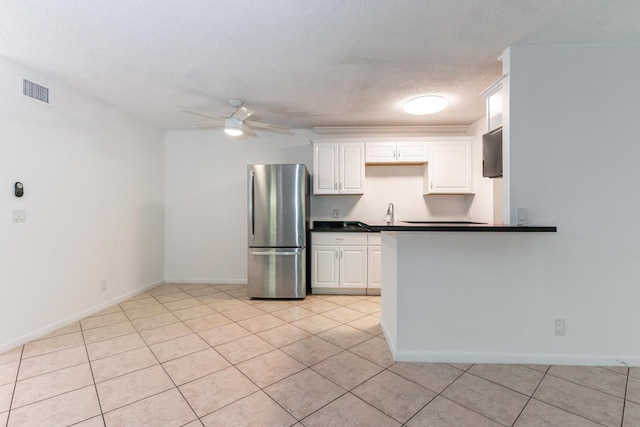 kitchen with stainless steel refrigerator, ceiling fan, white cabinets, and a textured ceiling