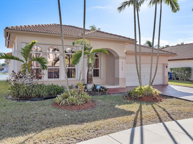 mediterranean / spanish house with a tiled roof, a garage, driveway, and stucco siding