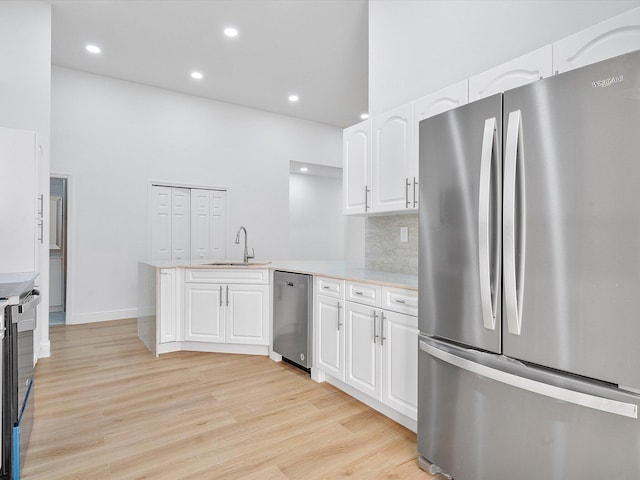 kitchen featuring sink, decorative backsplash, appliances with stainless steel finishes, light hardwood / wood-style floors, and white cabinetry