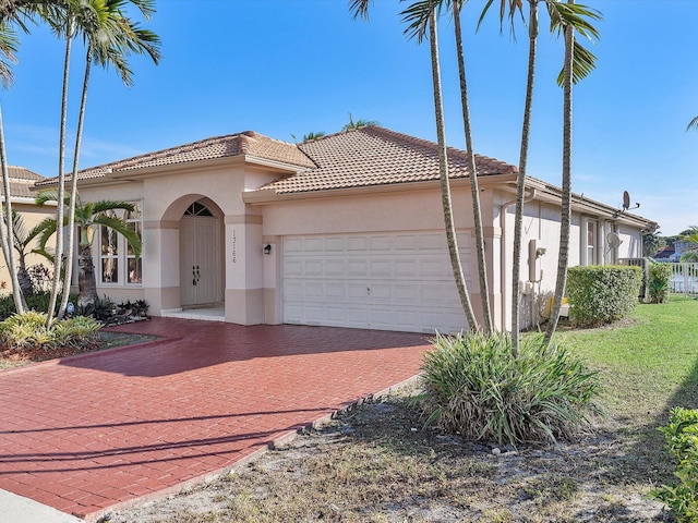 mediterranean / spanish house featuring stucco siding, decorative driveway, an attached garage, and a tile roof