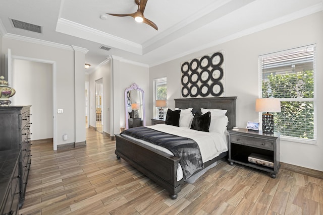 bedroom featuring multiple windows, a tray ceiling, ceiling fan, and ornamental molding