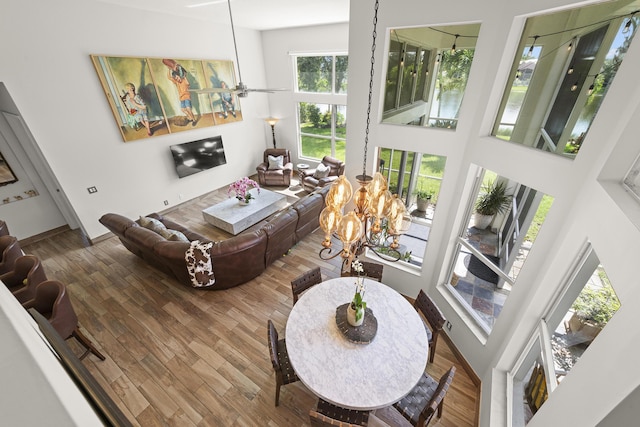 living room featuring a towering ceiling, wood-type flooring, and ceiling fan with notable chandelier