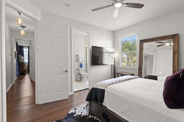 bedroom with ceiling fan, dark hardwood / wood-style floors, a textured ceiling, and connected bathroom