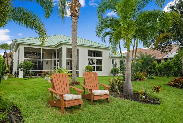 rear view of property with a lawn and a sunroom