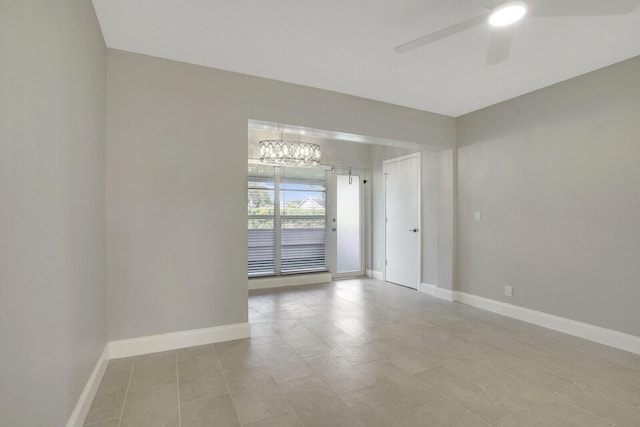 tiled empty room featuring ceiling fan with notable chandelier