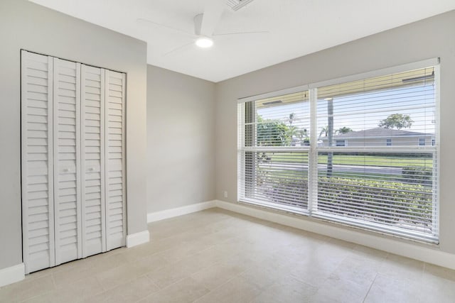 unfurnished bedroom with multiple windows, ceiling fan, a closet, and light tile patterned floors