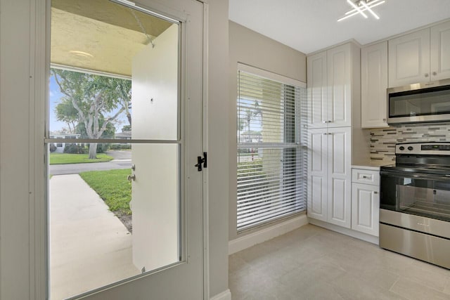 kitchen with decorative backsplash, white cabinets, and appliances with stainless steel finishes