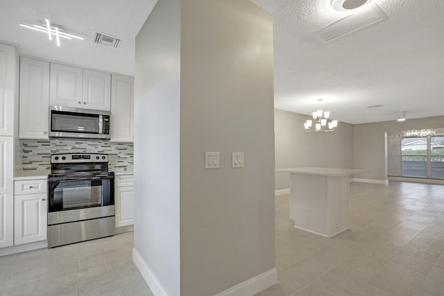 kitchen with a textured ceiling, tasteful backsplash, white cabinetry, stainless steel appliances, and a chandelier