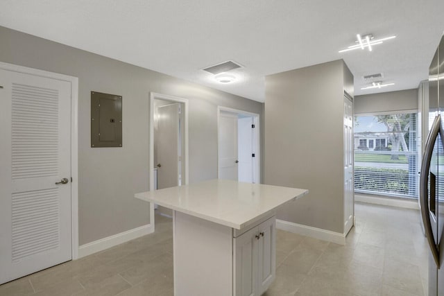 kitchen featuring stainless steel fridge, light tile patterned floors, white cabinets, electric panel, and a kitchen island