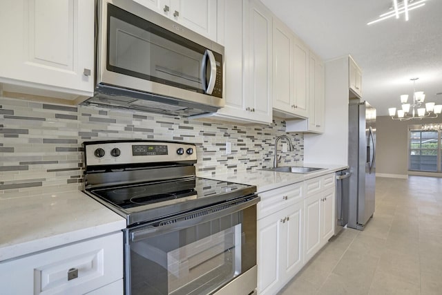 kitchen featuring appliances with stainless steel finishes, backsplash, sink, a notable chandelier, and white cabinets