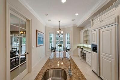 kitchen with crown molding, hanging light fixtures, dark stone counters, and an inviting chandelier