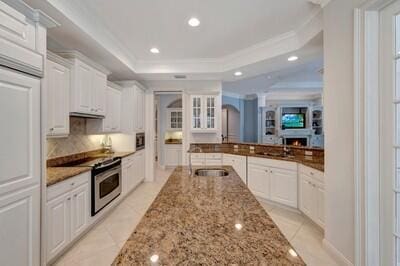 kitchen with white cabinets, stove, light stone countertops, and sink