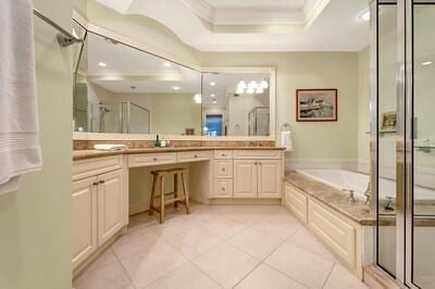 bathroom featuring vanity, a raised ceiling, tile patterned flooring, ornamental molding, and independent shower and bath