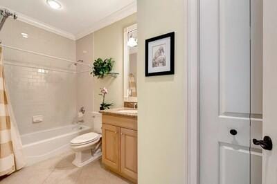 full bathroom featuring vanity, shower / bath combo with shower curtain, crown molding, tile patterned flooring, and toilet