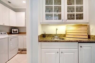 bar with white cabinets, washer and dryer, sink, and dark stone counters