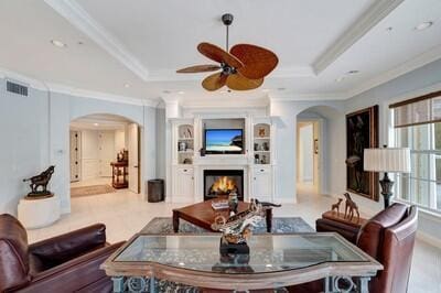 living room featuring a tray ceiling, ceiling fan, and ornamental molding