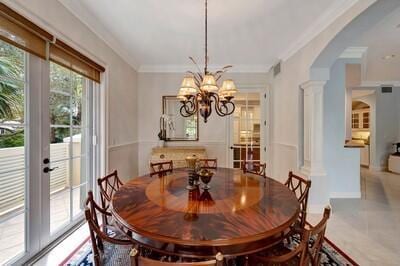 tiled dining area featuring ornate columns, crown molding, and a chandelier