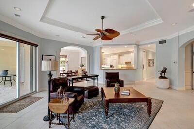 living room with a tray ceiling, ceiling fan, and ornamental molding