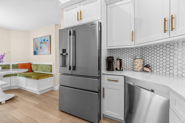 kitchen with tasteful backsplash, white cabinets, and appliances with stainless steel finishes