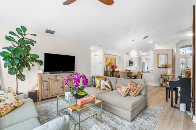 living room with ceiling fan, lofted ceiling, and light hardwood / wood-style flooring