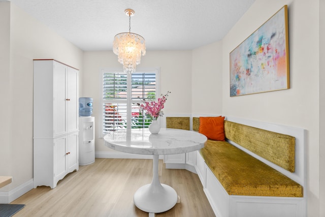 dining area with a textured ceiling, breakfast area, a notable chandelier, and light wood-type flooring