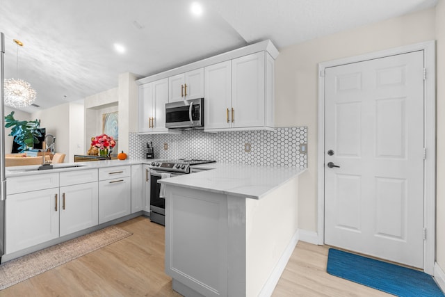 kitchen with kitchen peninsula, white cabinetry, light wood-type flooring, and appliances with stainless steel finishes