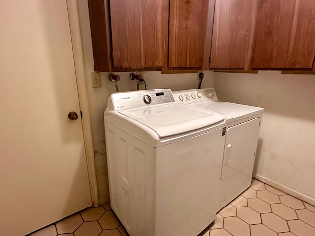 laundry room with cabinets, light tile patterned floors, and washer and dryer