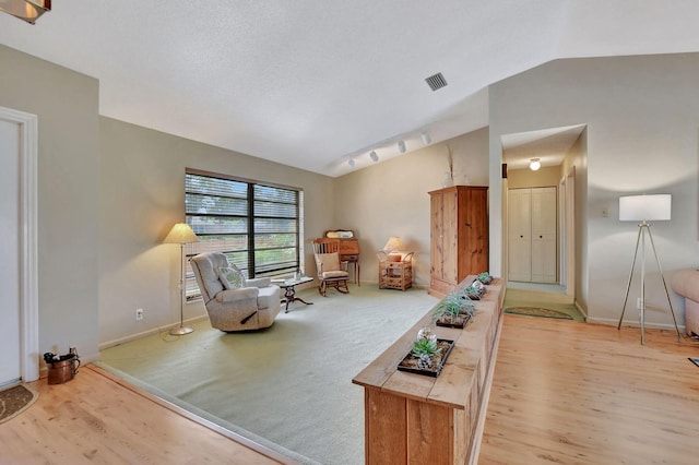 sitting room with vaulted ceiling and light colored carpet