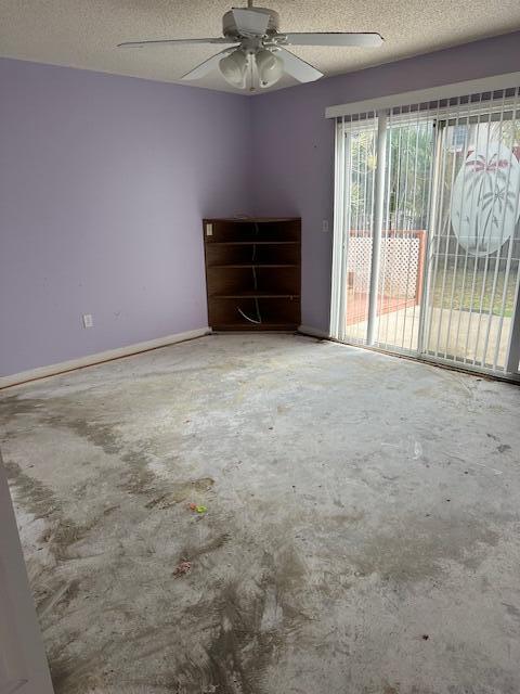 empty room with ceiling fan, a textured ceiling, and concrete floors