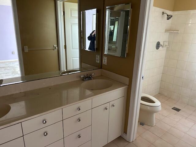 bathroom with tile patterned floors, vanity, toilet, and tiled shower