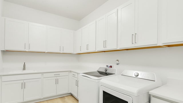 laundry room featuring cabinets, independent washer and dryer, light wood-type flooring, and sink