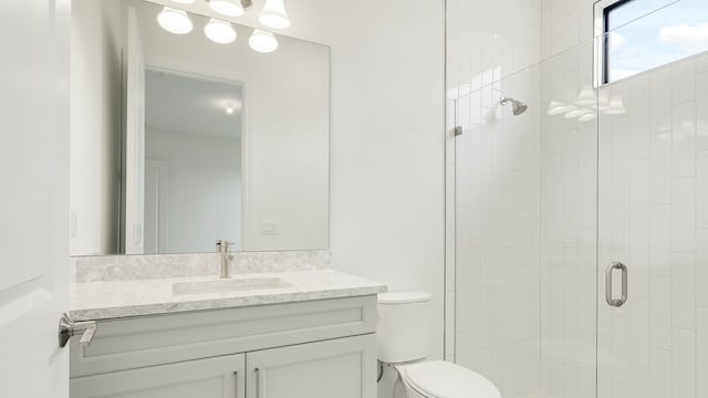 bathroom with vanity, toilet, and a shower with door