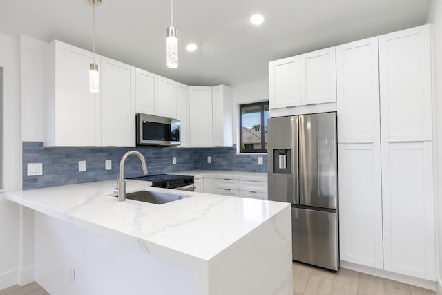 kitchen featuring white cabinets, pendant lighting, kitchen peninsula, and stainless steel appliances