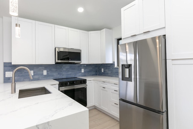 kitchen featuring light stone counters, white cabinets, pendant lighting, and appliances with stainless steel finishes